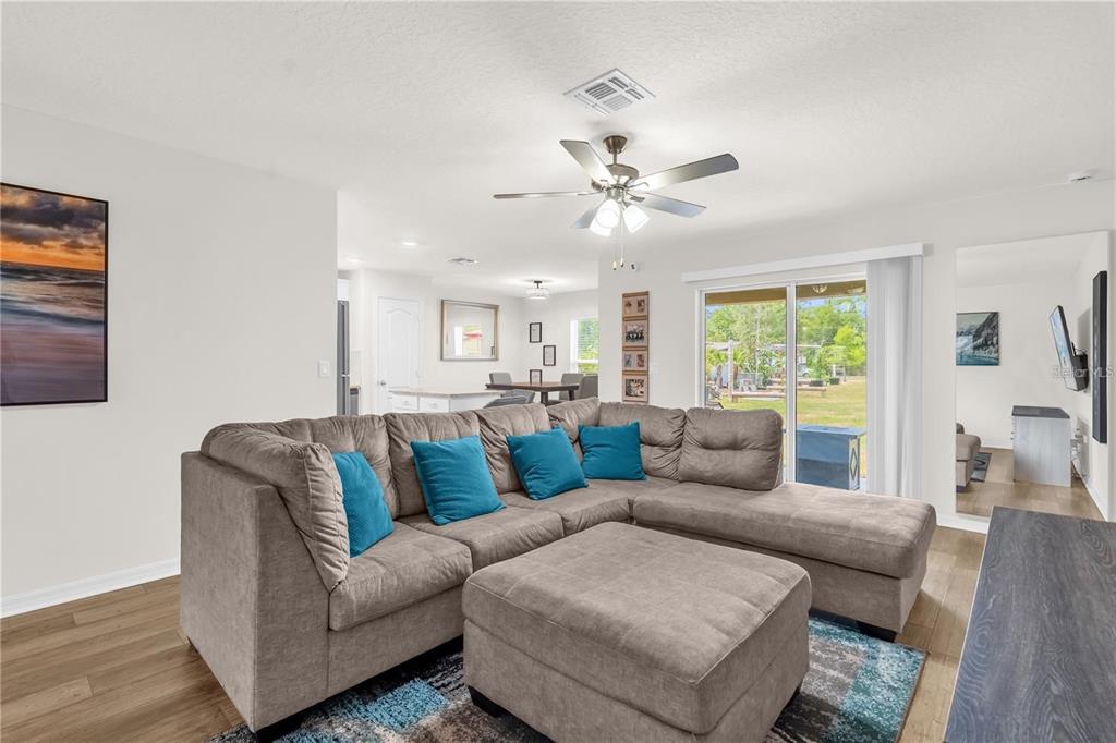 A living room features a gray sectional sofa, a matching ottoman, and a sliding glass door — 1898 9TH AVENUE, DELAND, FL