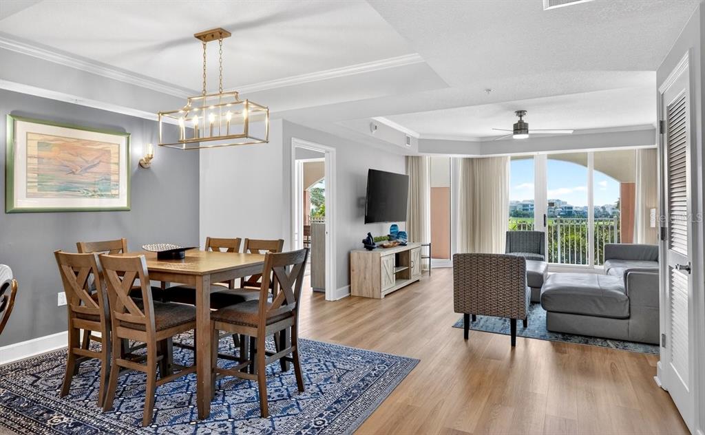 An open-concept living and dining area features wood-look flooring, a modern chandelier, and balcony access — 200 OCEAN CREST DRIVE UNIT 217, PALM COAST, FL