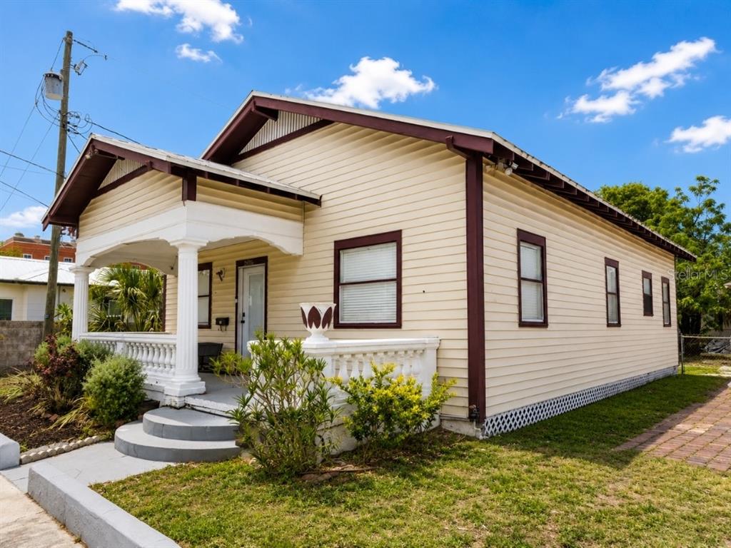 A light yellow house with a front porch and brown trim under a blue sky — 2806 N 17TH STREET, TAMPA, FL