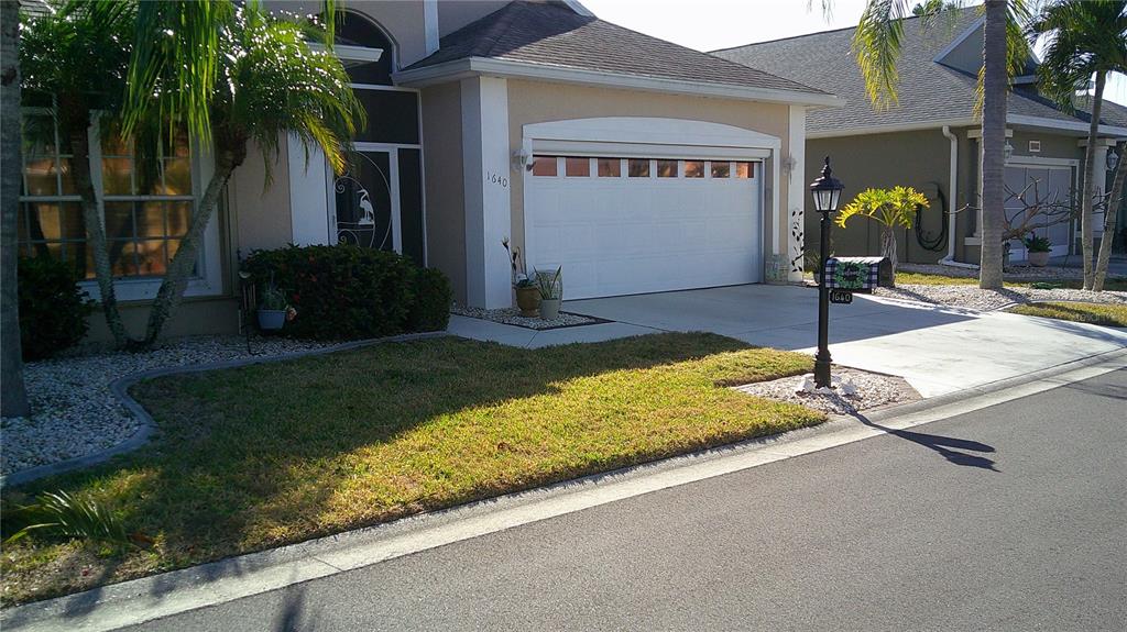 A single-story house with a white garage door, a lamp post, and a palm tree — 1640 PALACE COURT, PUNTA GORDA, FL