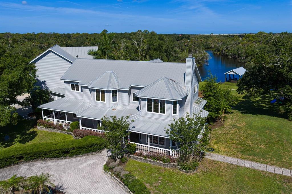 An aerial view of a gray two-story house with a metal roof near a river — 1030 MILL CREEK ROAD, BRADENTON, FL