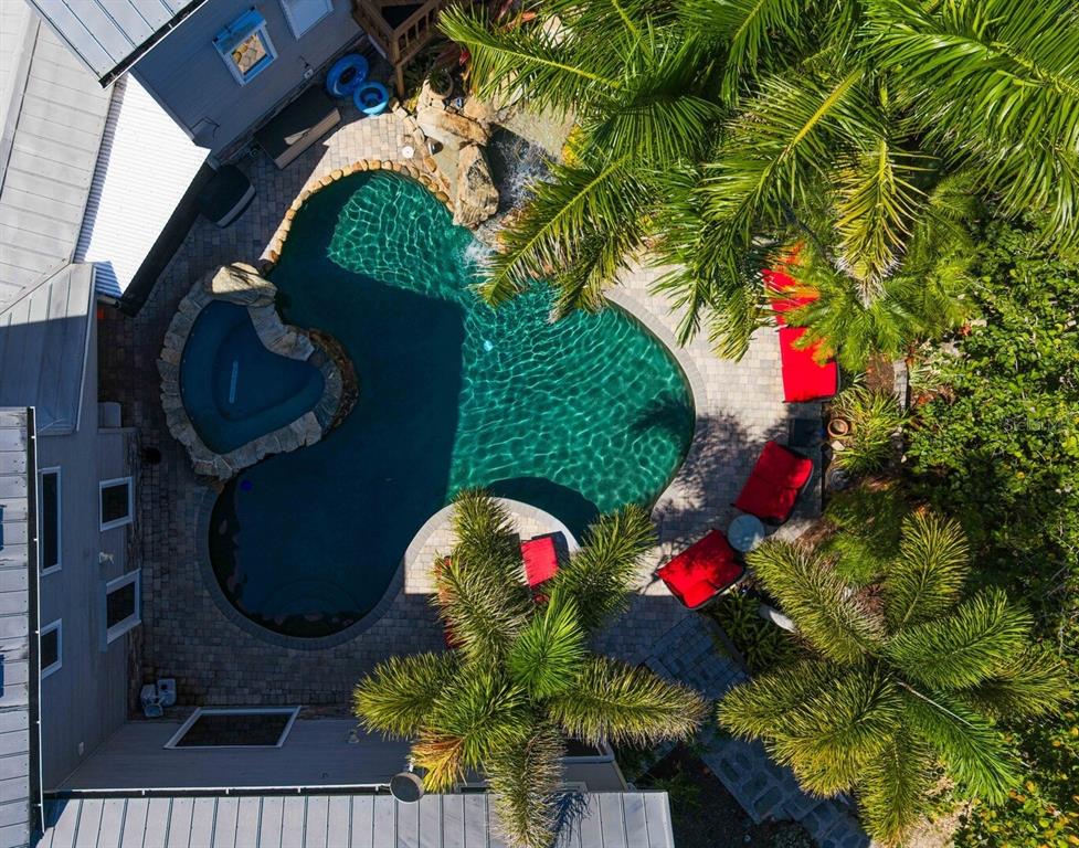 An aerial view of a backyard swimming pool with a spa, waterfall, and palm trees — 1030 MILL CREEK ROAD, BRADENTON, FL