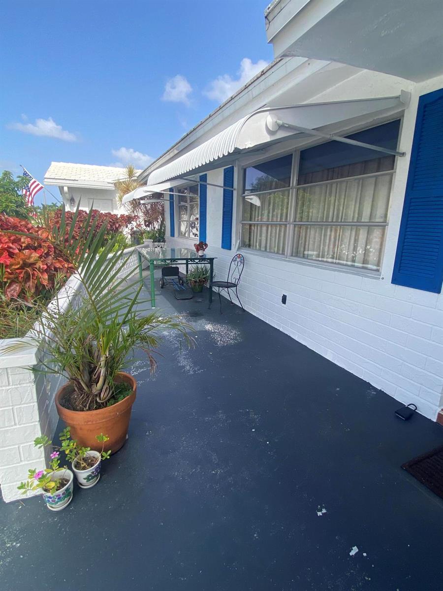 A patio with a dark floor, white brick walls, blue shutters, and metal window awnings — 2300 SW 19TH Avenue, Boynton Beach FL 33426, BOYNTON BEACH, FL