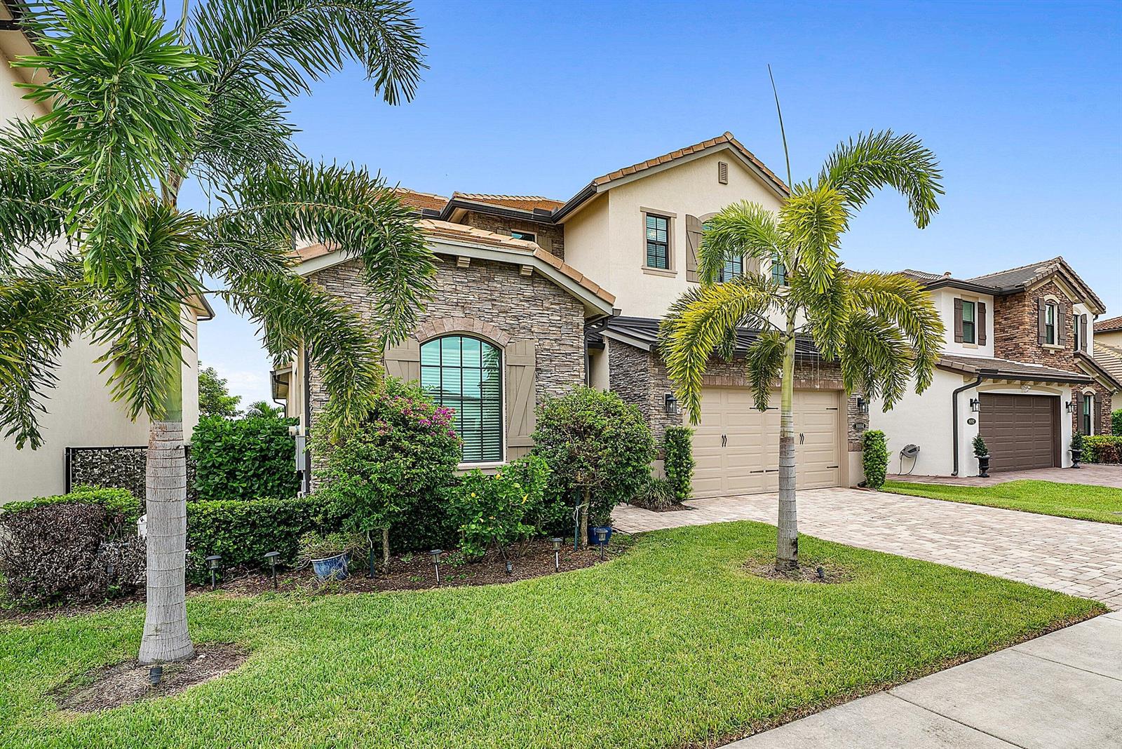 A two-story house with a stone facade, a two-car garage, and palm trees in front — 8884 Grand Prix Lane, Boynton Beach FL 33472, BOYNTON BEACH, FL