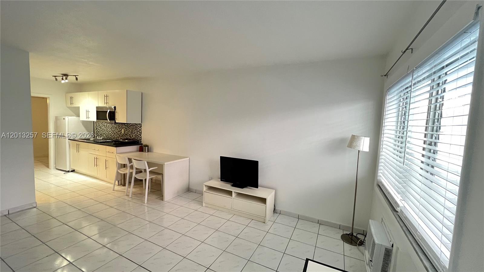 A small kitchen with white cabinets and a dining area sits beside a living space — 1234 Euclid Ave # 4, Miami Beach FL 33139, MIAMI BEACH, FL