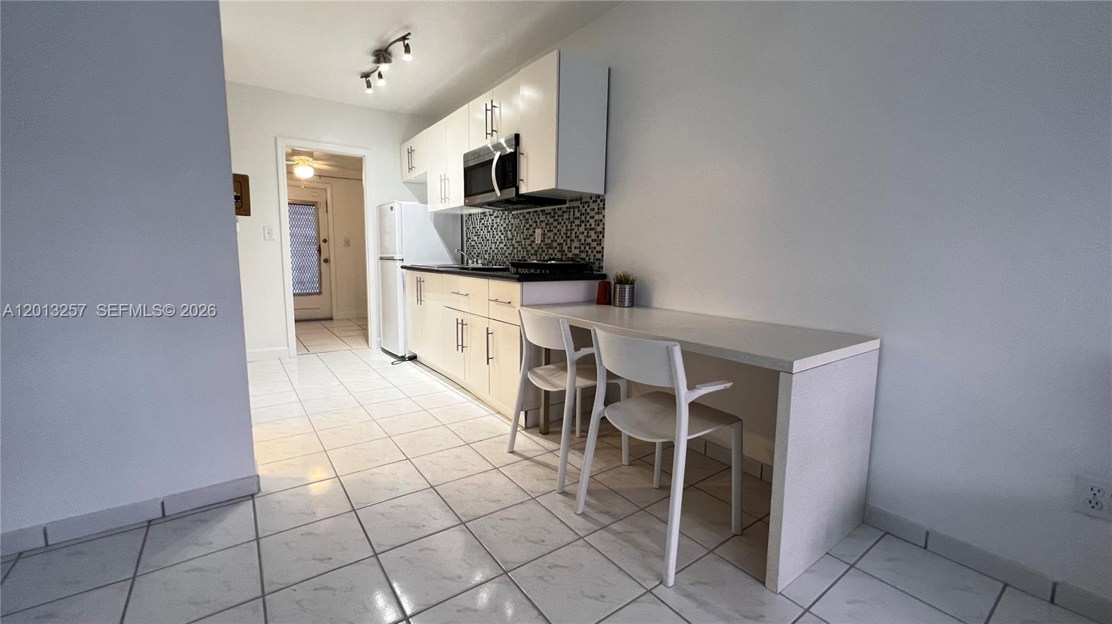 A kitchen features white cabinets, a tiled backsplash, and an attached white dining counter — 1234 Euclid Ave # 4, Miami Beach FL 33139, MIAMI BEACH, FL