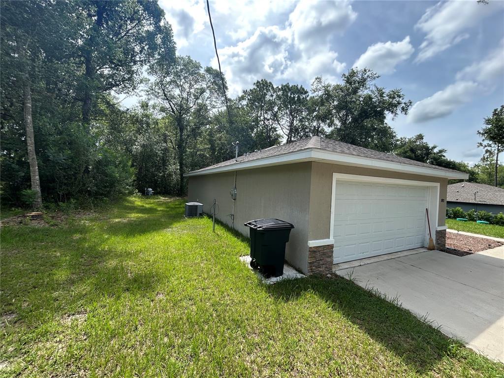 A detached garage with a white door and stone accents sits on a grassy lot — 5092 SW 197TH TERRACE, DUNNELLON, FL