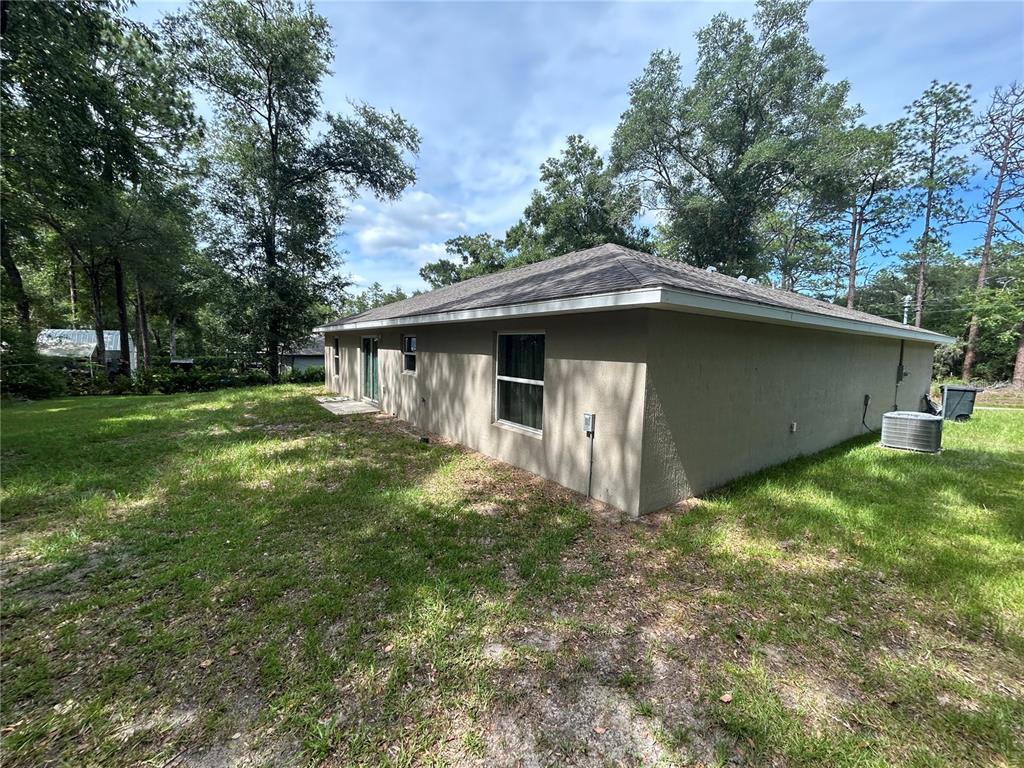 The exterior of a tan, single-story house with a hip roof and a grassy yard — 5092 SW 197TH TERRACE, DUNNELLON, FL