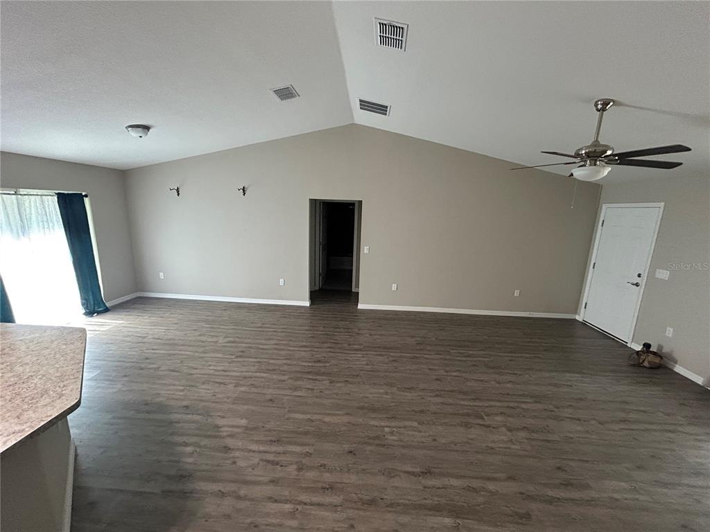 A spacious living room features vaulted ceilings, wood-look flooring, and a ceiling fan — 5092 SW 197TH TERRACE, DUNNELLON, FL
