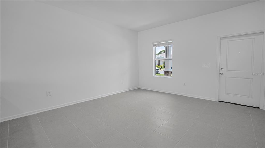 An empty room with white walls, gray tile flooring, a single window, and a door — 2136 RIDER RAIN LANE, APOPKA, FL