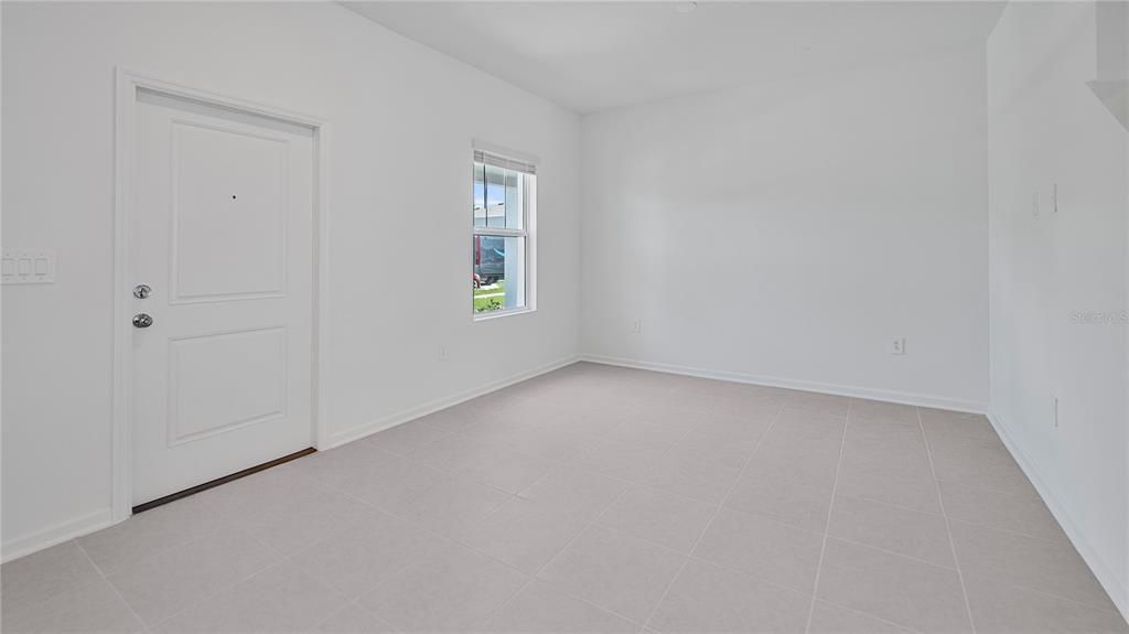 An empty room with white walls, light tile flooring, a window, and a white door — 2136 RIDER RAIN LANE, APOPKA, FL