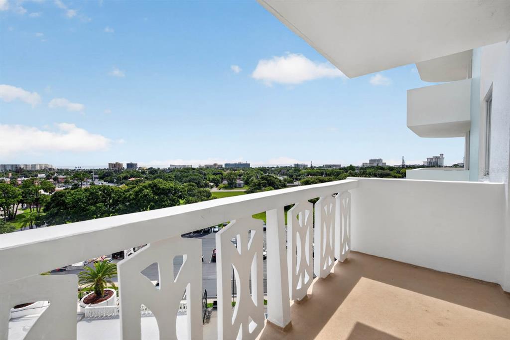 A high-rise balcony with white decorative railings overlooks a suburban landscape under a blue sky — 925 N HALIFAX AVENUE UNIT 710, DAYTONA BEACH, FL