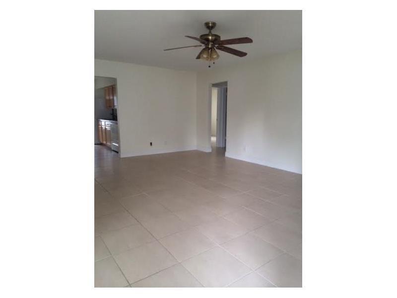 An empty room with light-colored tile flooring, white walls, and a ceiling fan — LAUDERDALE BY THE SEA, FL