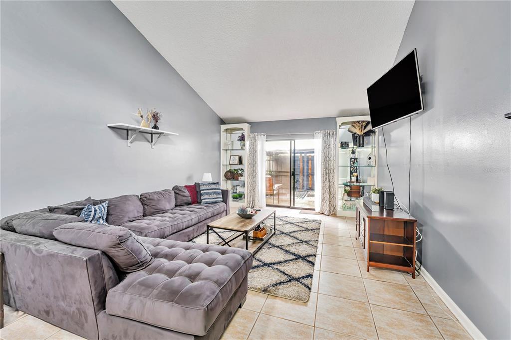 A living room features a gray sectional sofa, a coffee table, and a wall-mounted television — 701 SAINT MICHAEL LANE, ALTAMONTE SPRINGS, FL