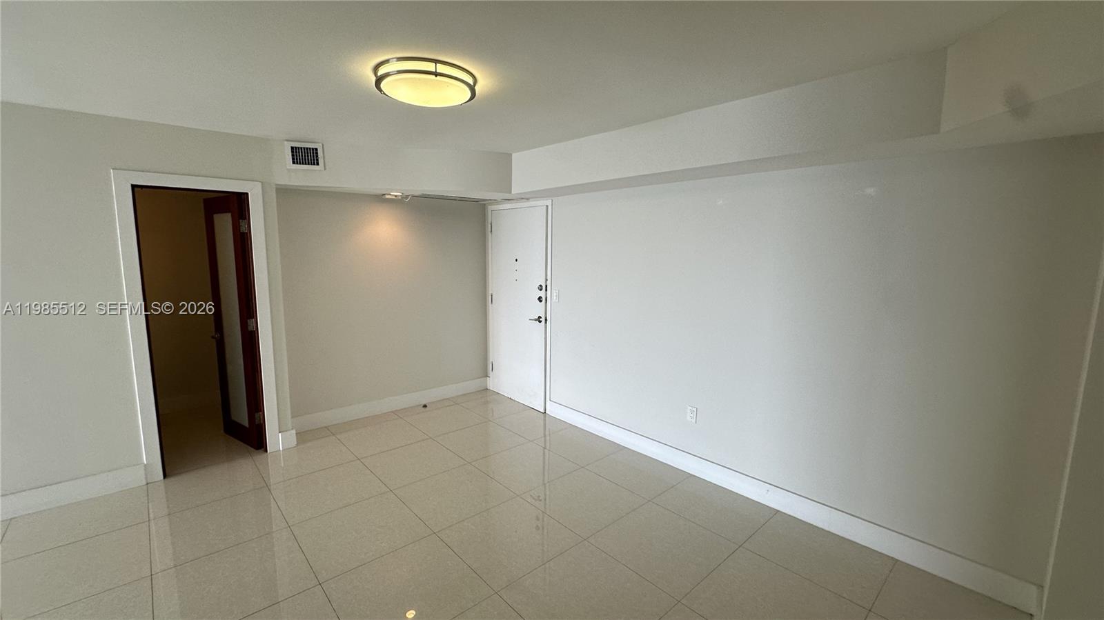 An empty room features white walls, light-colored tile flooring, a ceiling light fixture, and two doors — 2333 Brickell Ave # 1009, Miami FL 33129, MIAMI, FL