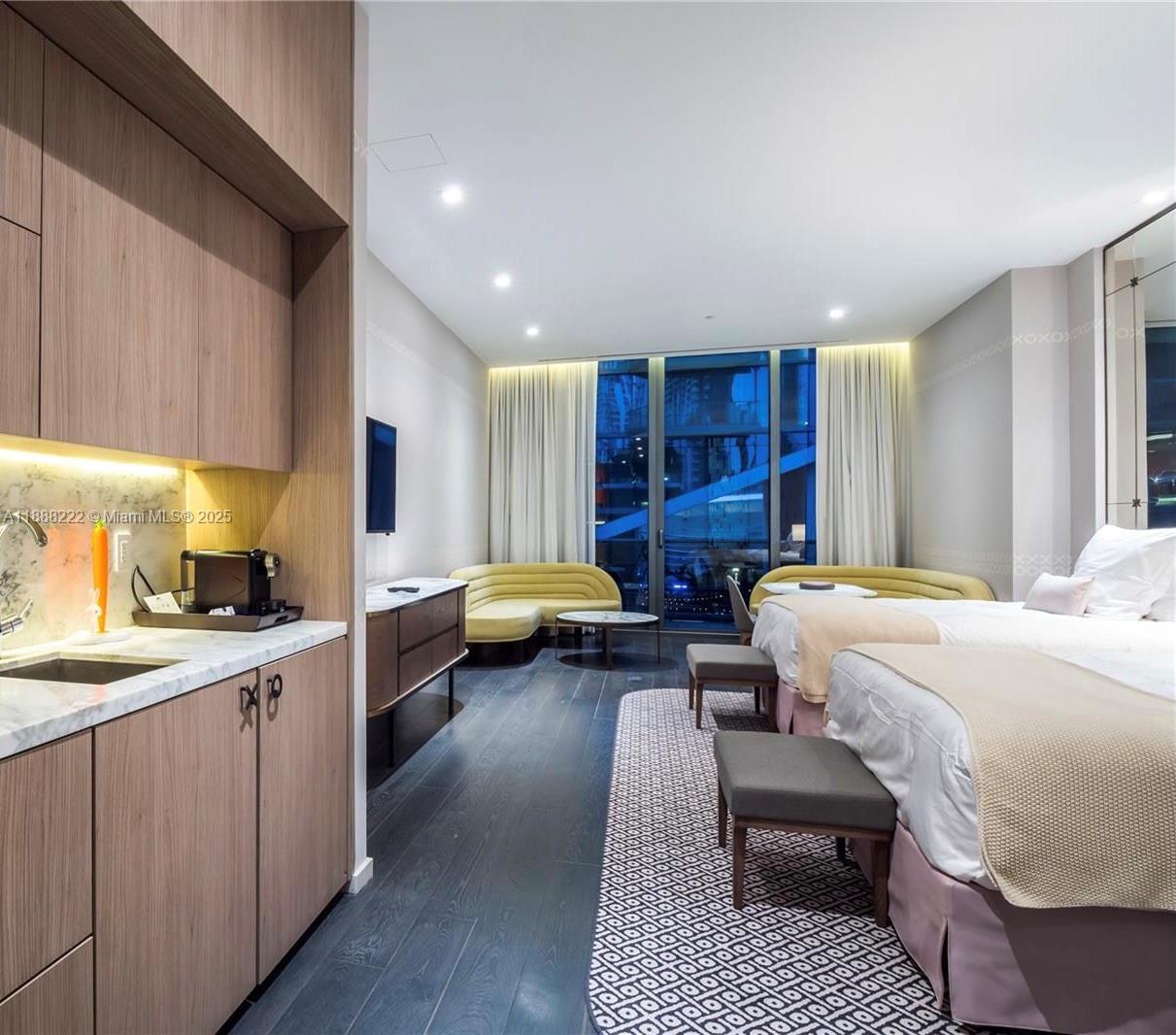 A hotel room features two beds, a kitchenette, dark wood floors, and floor-to-ceiling windows — 801 S Miami Ave # 712, Miami FL 33130, MIAMI, FL