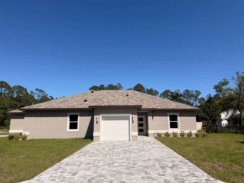 A single-story house with a gray stucco exterior, a paved driveway, and a one-car garage — 2 SLATE WOOD COURT UNIT A, PALM COAST, FL
