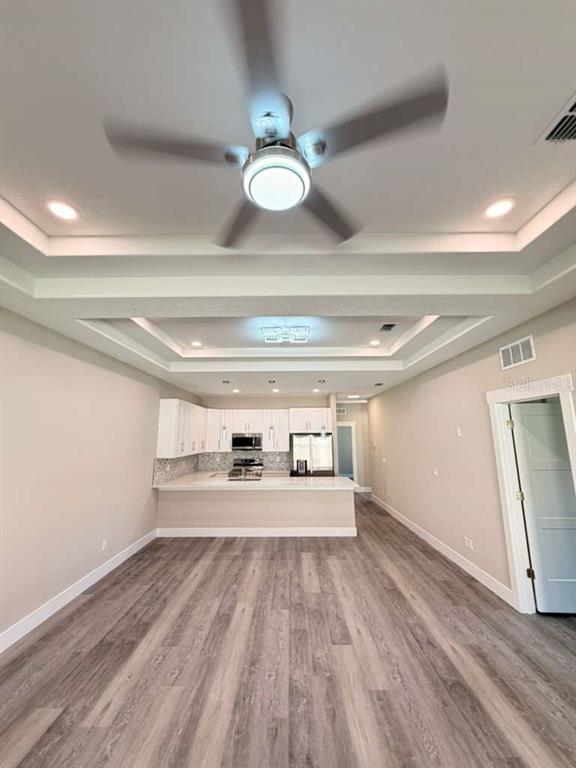 An open-concept kitchen with white cabinets and a tray ceiling with a ceiling fan — 2 SLATE WOOD COURT UNIT A, PALM COAST, FL