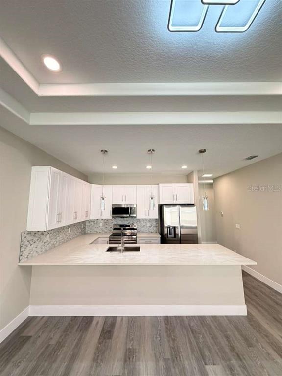 A modern kitchen features white cabinets, stainless steel appliances, and a large peninsula countertop — 2 SLATE WOOD COURT UNIT A, PALM COAST, FL