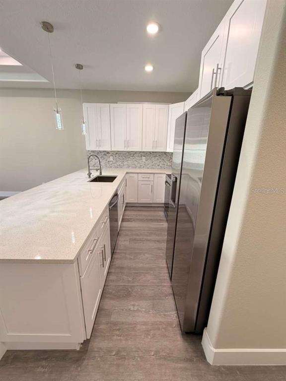 A modern kitchen features white cabinets, a long quartz island, and stainless steel appliances — 2 SLATE WOOD COURT UNIT A, PALM COAST, FL
