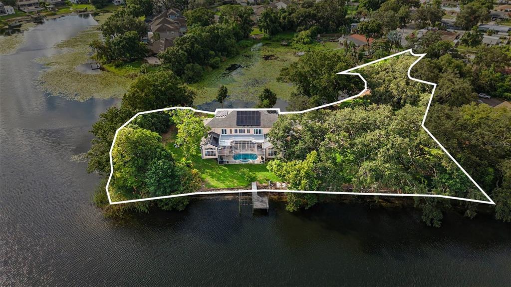 An aerial view shows a house with a pool and dock on a lakefront lot — 9723 YESHUA WAY, TAMPA, FL