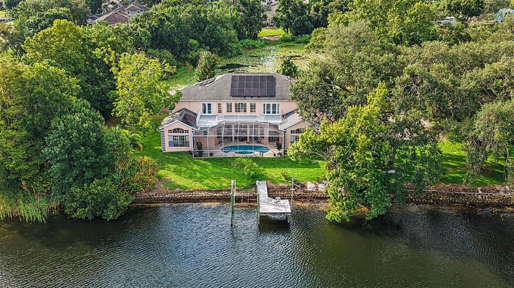 An aerial view of a two-story house with a pool, solar panels, and a private dock — 9723 YESHUA WAY, TAMPA, FL