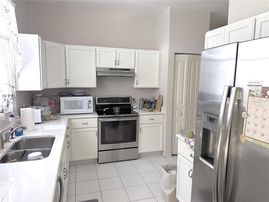 A kitchen features white cabinets, stainless steel appliances, and a tiled floor — 4968 EBENSBURG DRIVE, TAMPA, FL