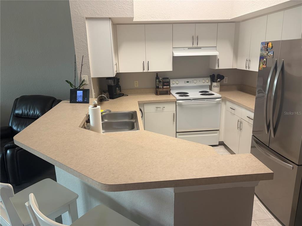A kitchen features white cabinets, a light-colored countertop, and stainless steel appliances — 4140 CENTRAL SARASOTA PARKWAY UNIT 1235, SARASOTA, FL
