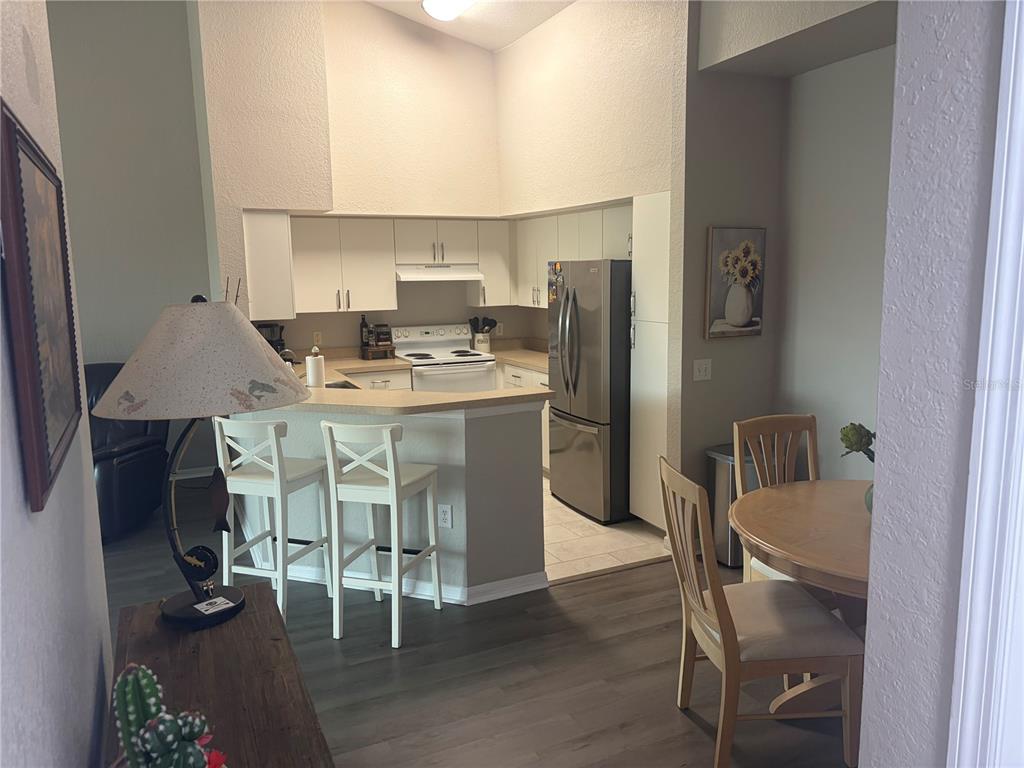 A kitchen with white cabinets, stainless steel appliances, and a breakfast bar with two chairs — 4140 CENTRAL SARASOTA PARKWAY UNIT 1235, SARASOTA, FL