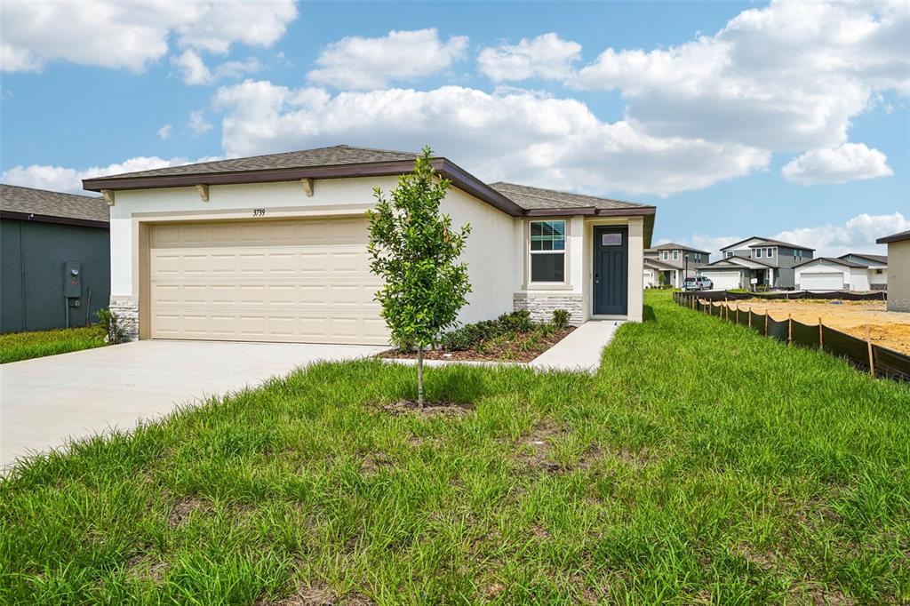 A single-story house with a beige stucco exterior, a two-car garage, and a front lawn — 3739 MOSCATO DRIVE, BROOKSVILLE, FL