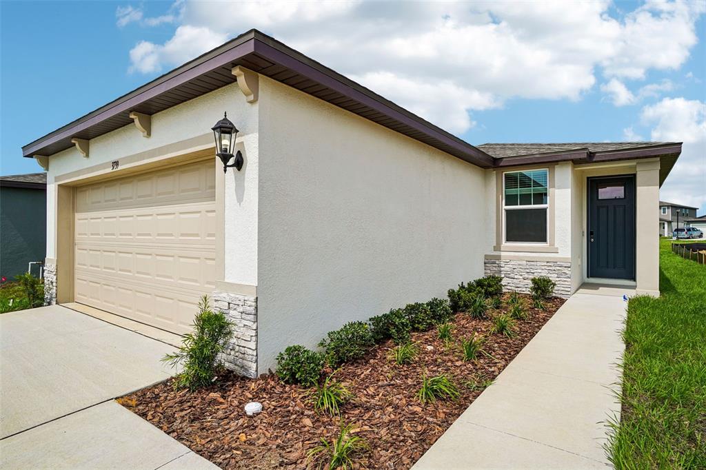 The exterior of a single-story house features a garage, stone accents, and a front walkway — 3739 MOSCATO DRIVE, BROOKSVILLE, FL
