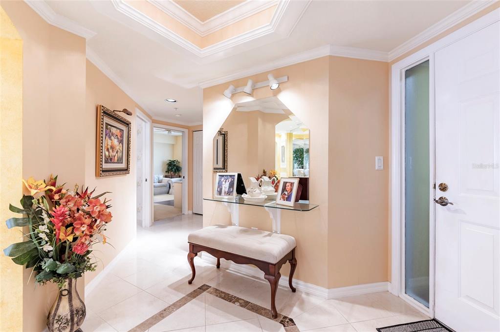 A foyer with tile flooring, a glass console table, a bench, and a wall mirror — 16750 GULF BOULEVARD UNIT 414, NORTH REDINGTON BEACH, FL