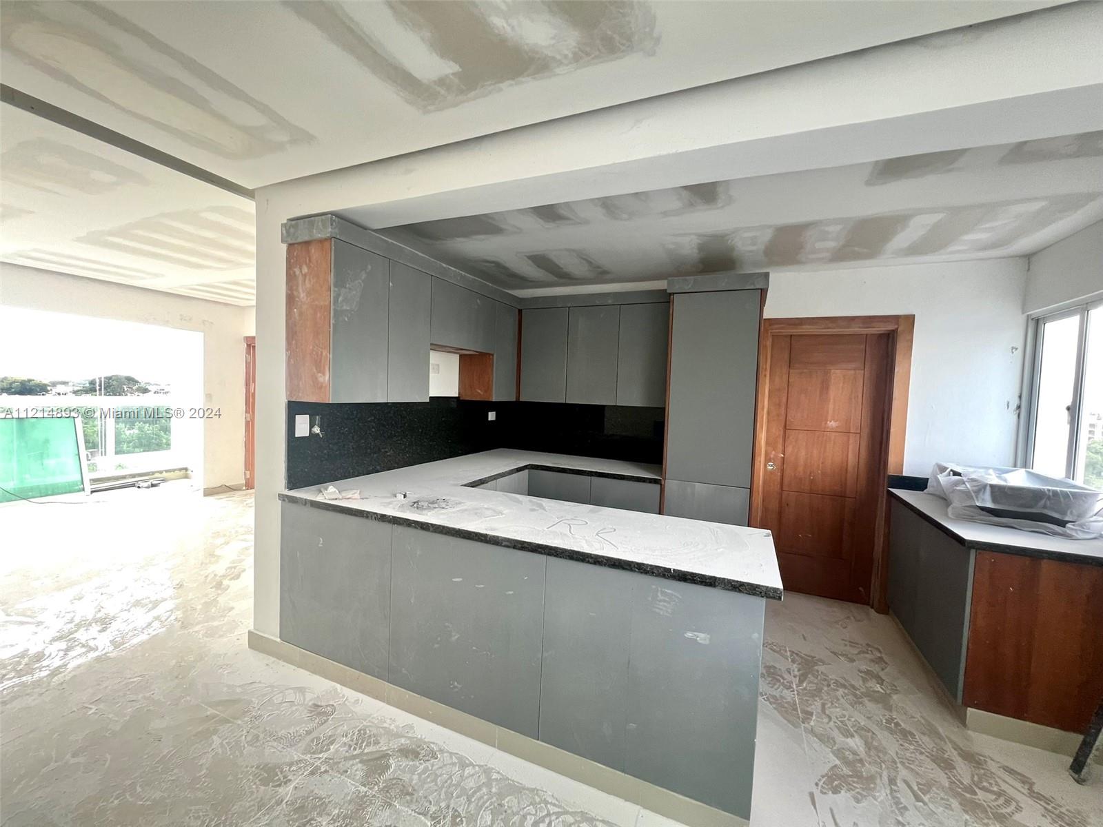 A kitchen under renovation features gray cabinets, black countertops, and unfinished drywall ceilings — Calle .. Esquina D-1 Villa Olimpica, Santiago PH, DO, DO