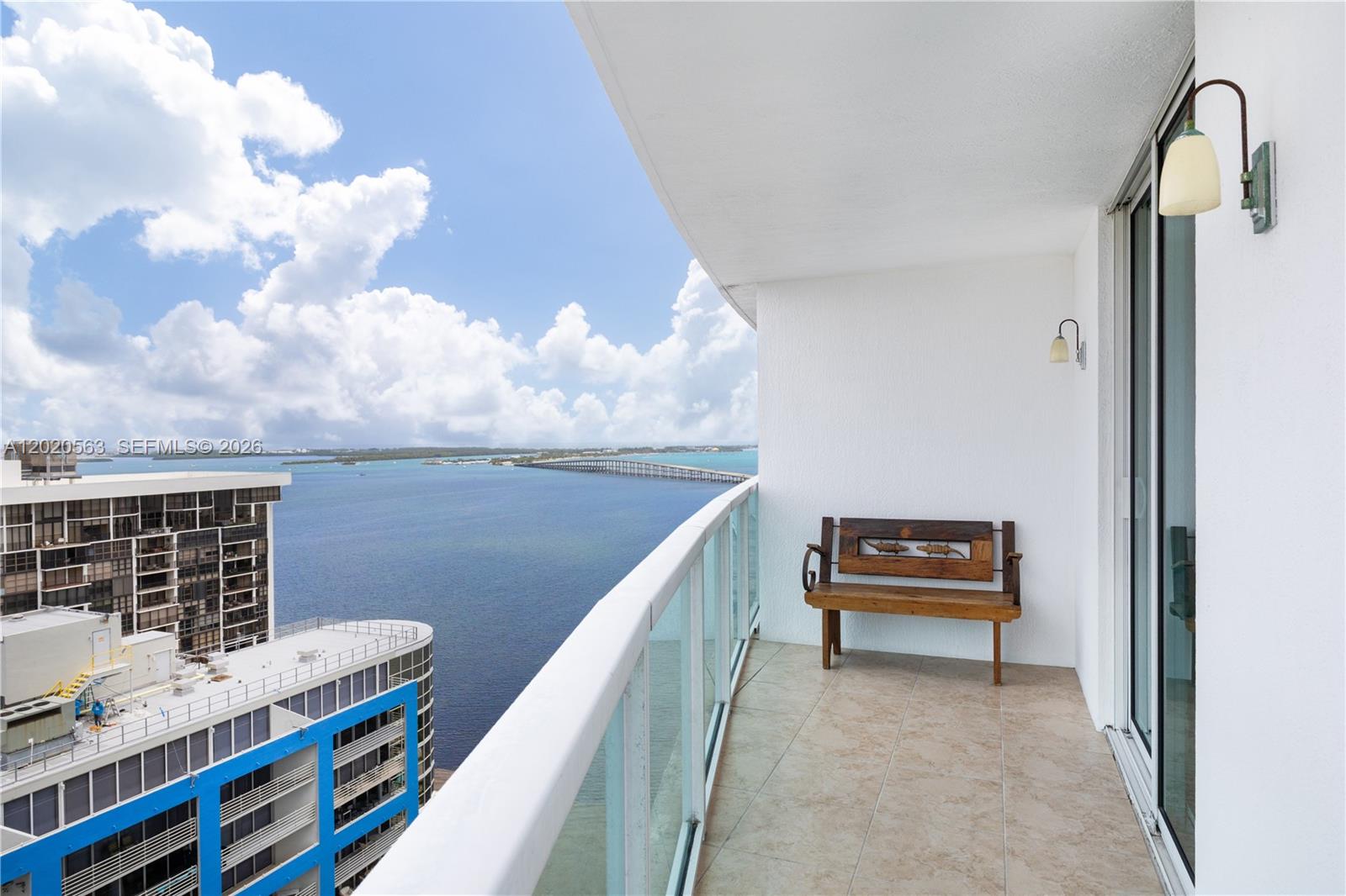 A balcony with a wooden bench overlooks a body of water and a bridge — 2101 NE Brickell Ave # 2302, Miami FL 33129, MIAMI, FL