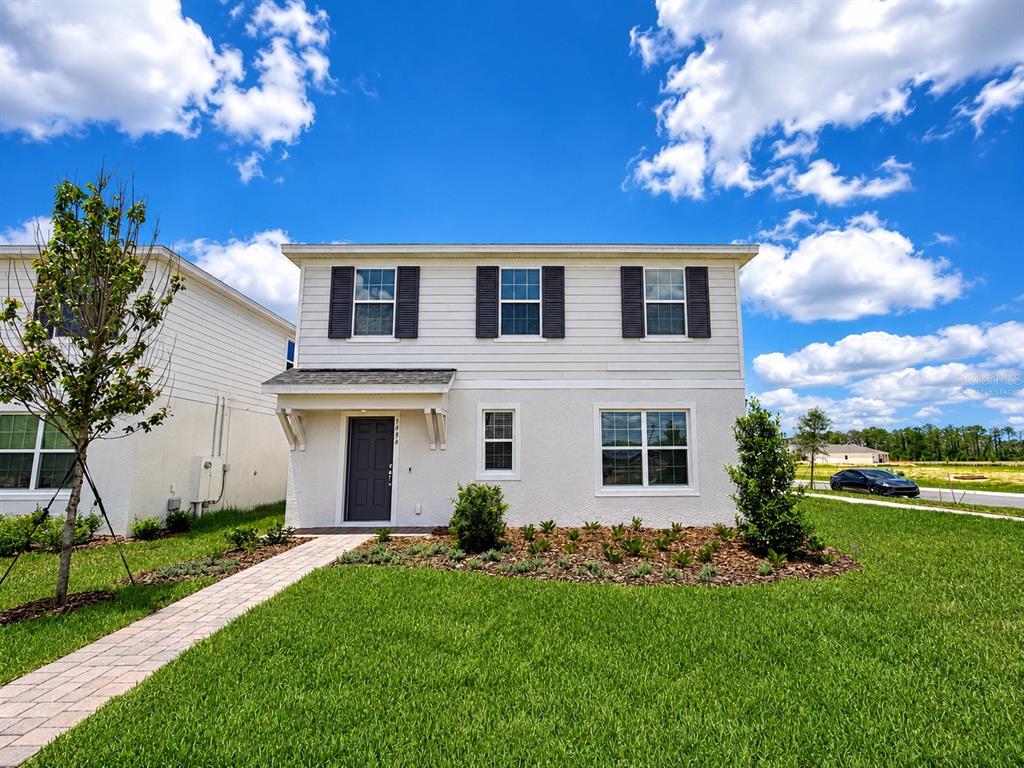 A two-story house with a white stucco and siding exterior, dark shutters, and a front walkway — 5646 ENCHANTED MEADOW ALY, CLERMONT, FL