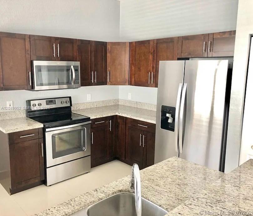 A kitchen features dark wood cabinets, granite countertops, and stainless steel appliances — 3965 NE 15th St, Homestead FL 33033, HOMESTEAD, FL