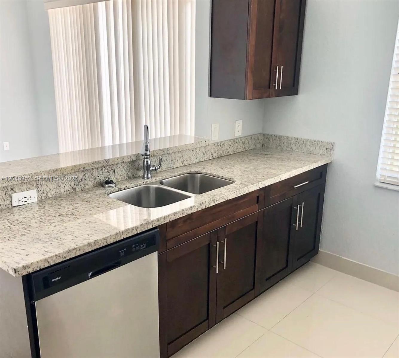 A kitchen features dark wood cabinets, granite countertops, a stainless steel sink, and a dishwasher — 3965 NE 15th St, Homestead FL 33033, HOMESTEAD, FL