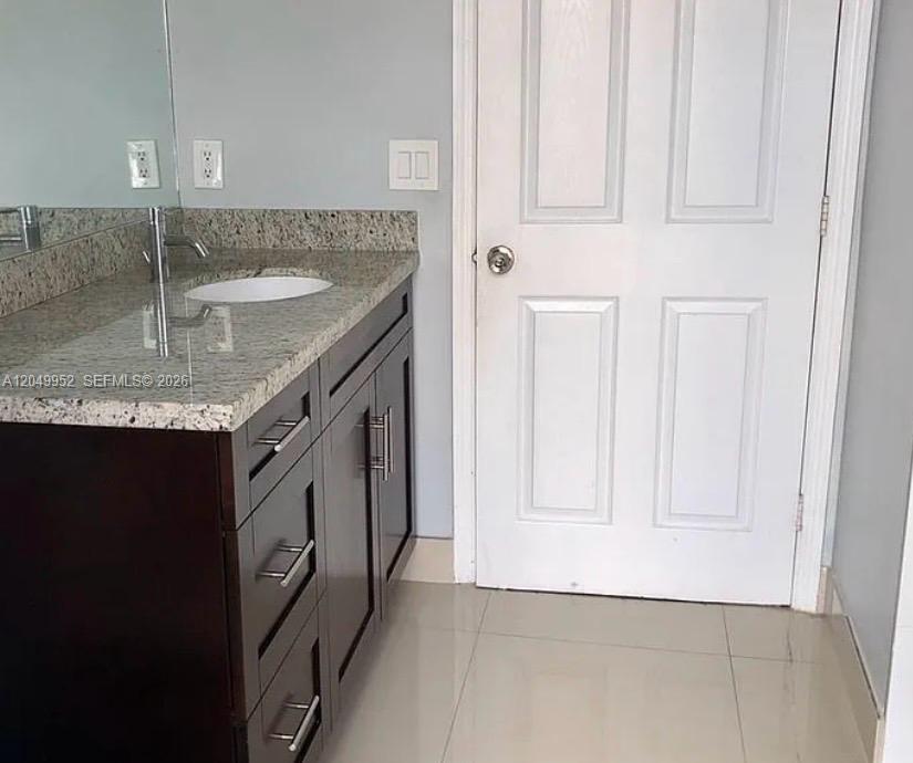 A bathroom features a granite-topped vanity with dark wood cabinets and a white door — 3965 NE 15th St, Homestead FL 33033, HOMESTEAD, FL