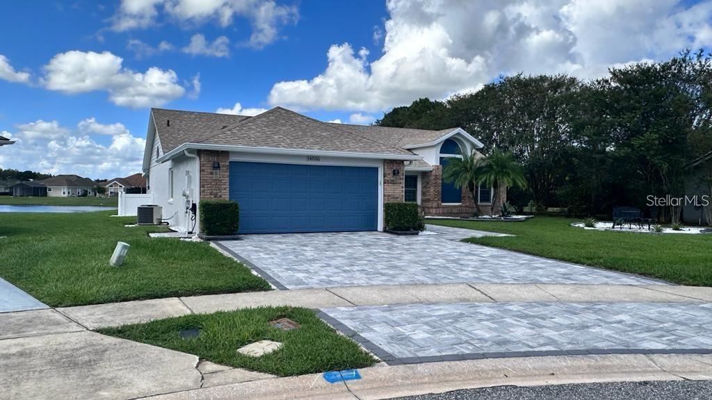 A single-story house with a blue garage door and a paved driveway under a cloudy sky — 14506 TIMUCUA COURT, ORLANDO, FL