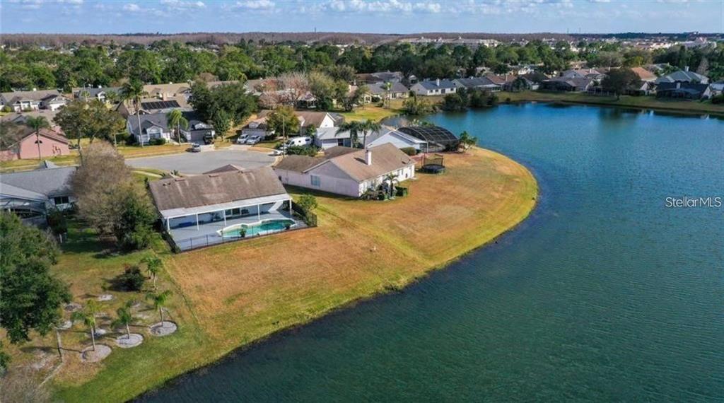 An aerial view shows two houses with swimming pools situated along the edge of a lake — 14506 TIMUCUA COURT, ORLANDO, FL