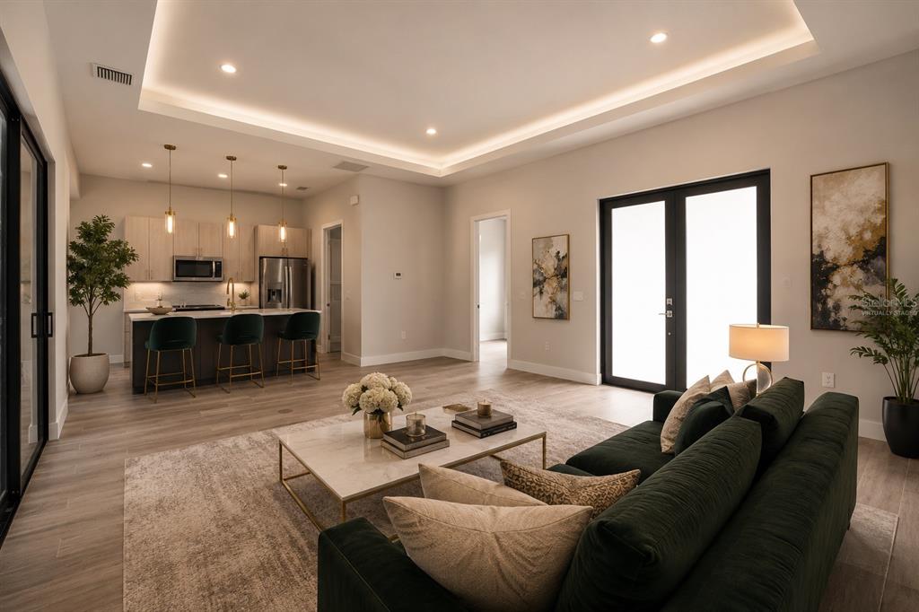 A modern open-concept living room and kitchen featuring light wood floors and a dark sofa — 14319 ALLENSWORTH AVENUE, PORT CHARLOTTE, FL