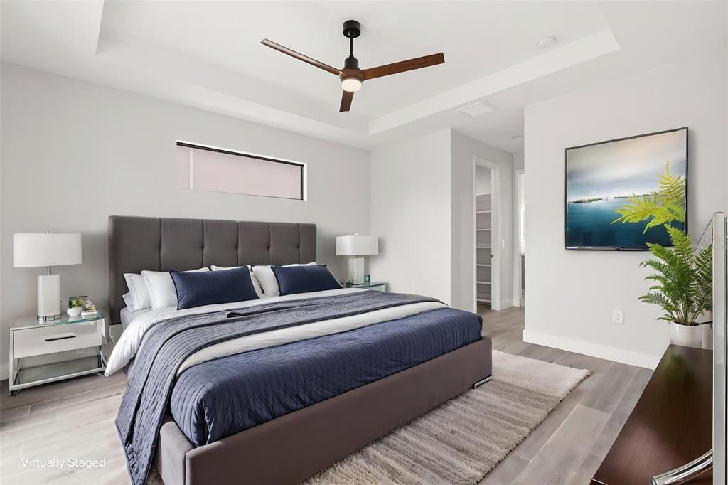 A modern bedroom features a gray upholstered bed, a ceiling fan, and light wood flooring — 14319 ALLENSWORTH AVENUE, PORT CHARLOTTE, FL