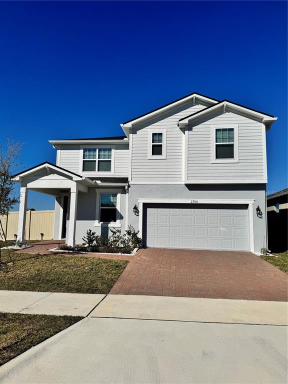 A two-story house features a gray stucco and siding exterior with a brick paver driveway — 2700 SWEET ACACIA DRIVE, CLERMONT, FL