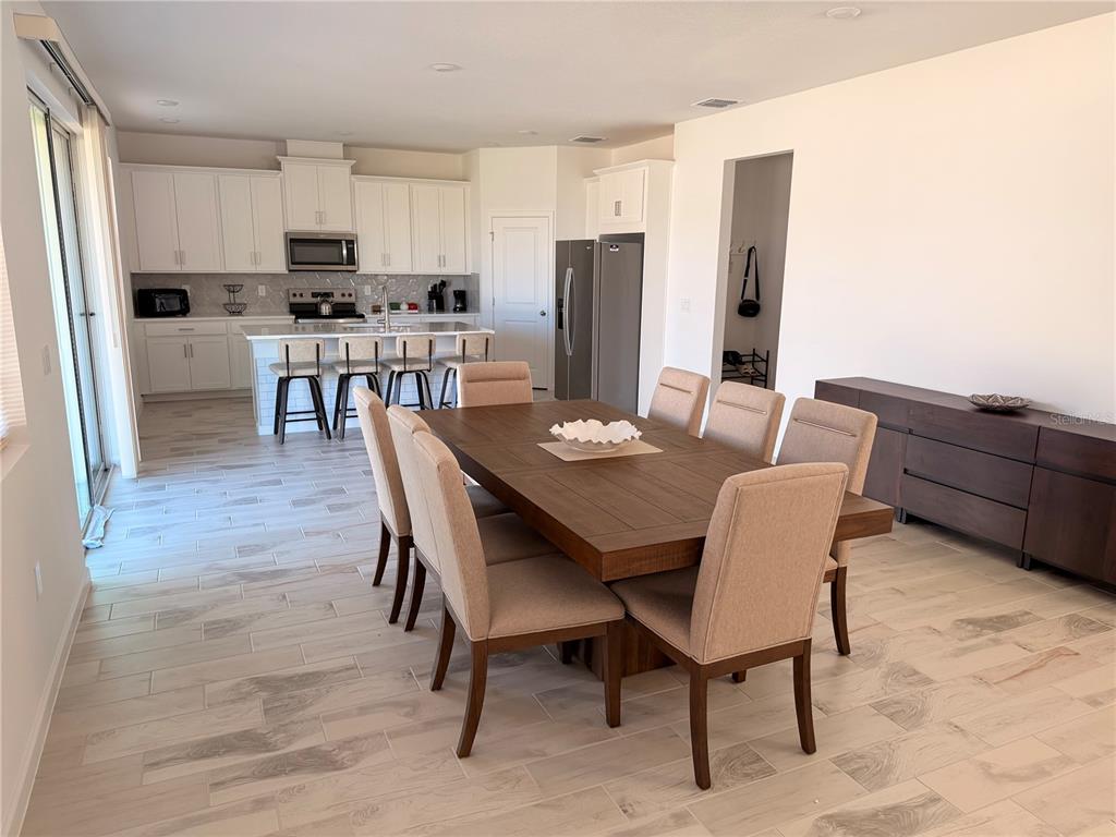 A dining area with a wooden table and chairs sits adjacent to an open kitchen — 2700 SWEET ACACIA DRIVE, CLERMONT, FL