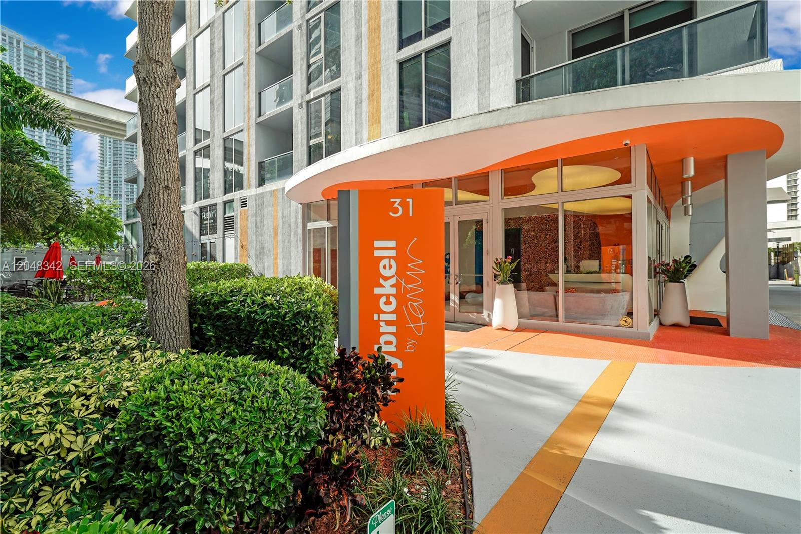 An orange sign stands before the glass-walled entrance of a modern apartment building — 31 SE 6th St # 2706, Miami FL 33131, MIAMI, FL