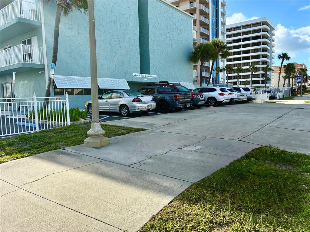 A teal condominium building exterior with a parking lot and surrounding palm trees — 3727 S ATLANTIC AVE UNIT 1120, DAYTONA BEACH, FL