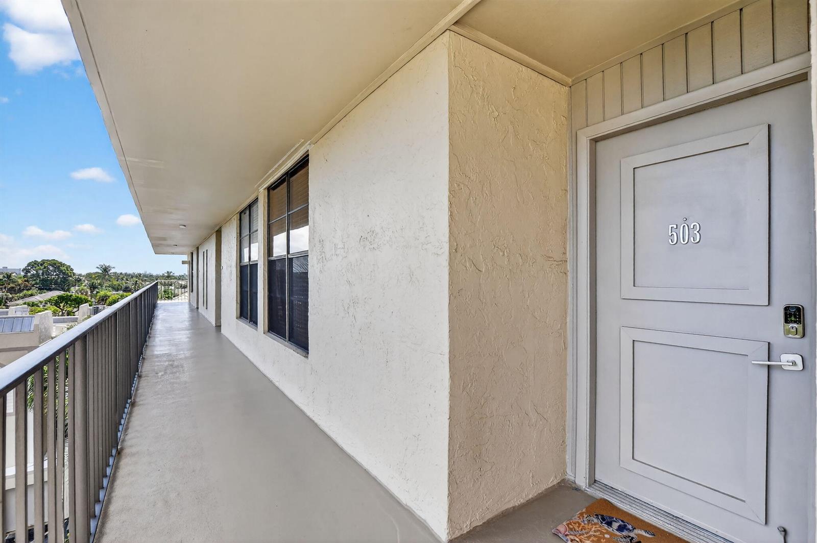 An outdoor apartment balcony features a gray door marked 503 and a metal railing — 20 Royal Palm Way # 503, Boca Raton FL 33432, BOCA RATON, FL
