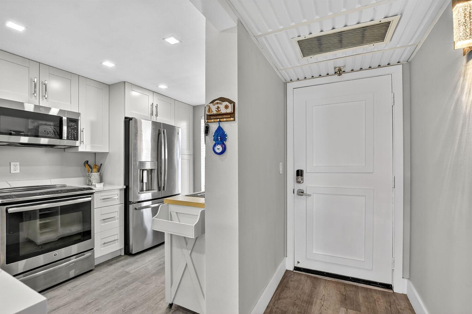 A kitchen with white cabinets, stainless steel appliances, and a white door in the foreground — 20 Royal Palm Way # 503, Boca Raton FL 33432, BOCA RATON, FL