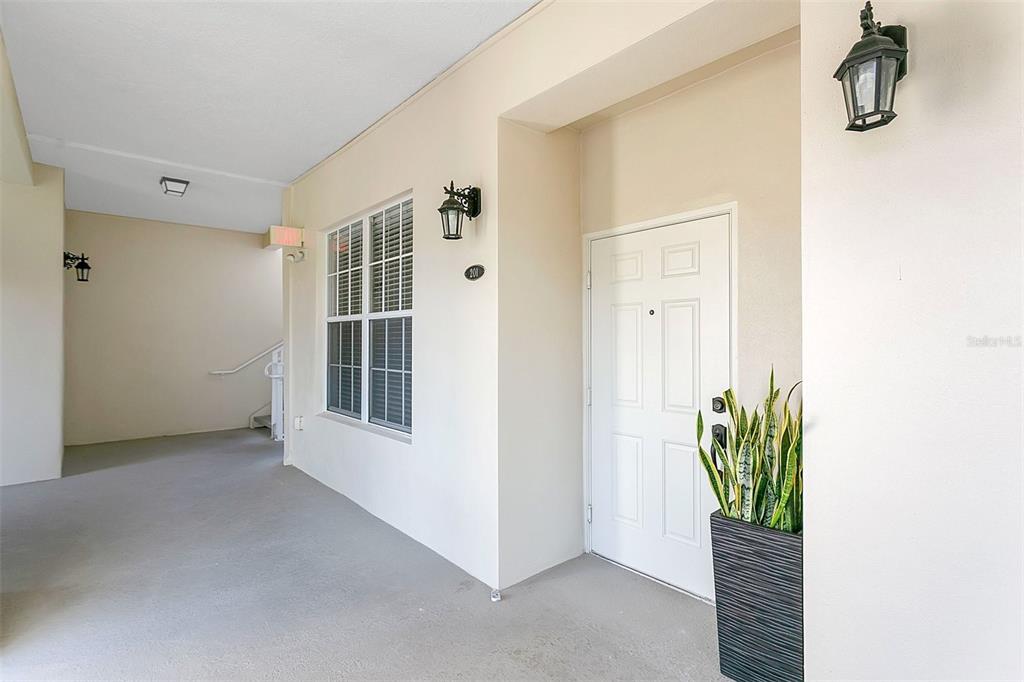 A three-story building exterior features stacked balconies with white railings and glass-paned double doors — 4392 WARDELL PLACE UNIT 201, ORLANDO, FL