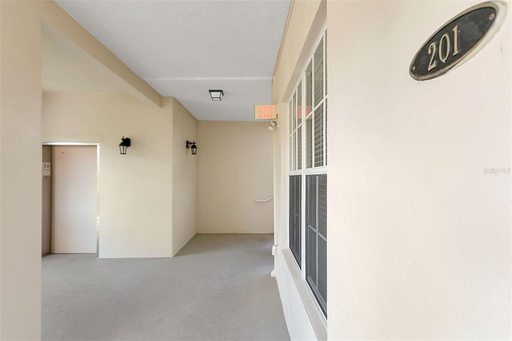 An outdoor apartment hallway features a beige wall with unit number 201 and an exit sign — 4392 WARDELL PLACE UNIT 201, ORLANDO, FL